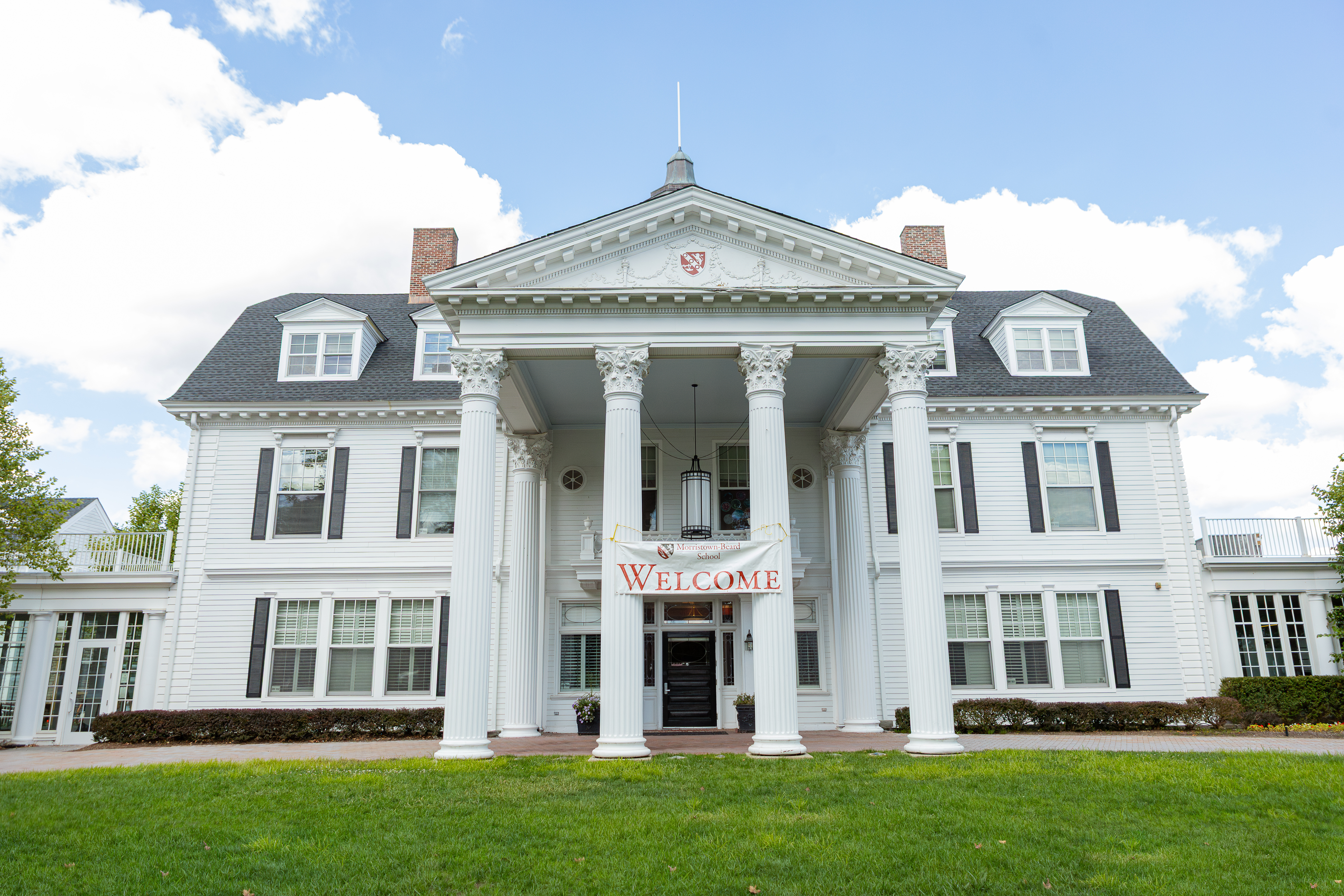 The front of stately Beard Hall, the most recognizable building for MBS. It is white with four columns and a cupola.